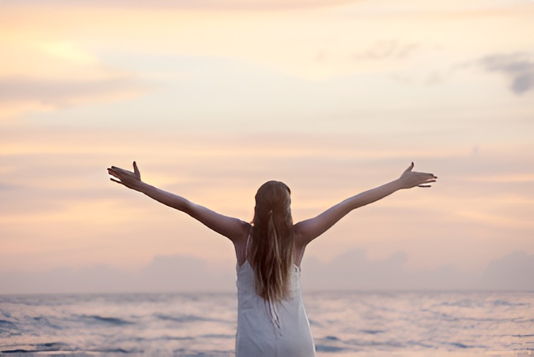 woman with arms out in front of the sea